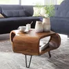 A wooden coffee table with decorative vases and a cup of coffee on it, placed in a living room setting with a sofa in the background.