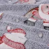 A close-up view of a soft, grey blanket with a Christmas-themed pattern featuring Santa Claus and Christmas trees. Náhled obrázku produktu