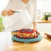 A person is holding a cake dome over a decorated cake on a cake stand. Náhľad obrázku produktu