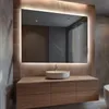 A modern bathroom vanity with a large, illuminated mirror above a sink and wooden cabinets. Produktbild-Vorschau