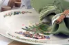 A close-up of a Christmas-themed plate setting with a green napkin and cinnamon stick. Produktbild-Vorschau