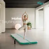 A woman is performing a yoga pose on an air track mat in a bright, modern room. Produktbild-Vorschau