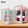 Two pink picture frames with cartoon animal drawings inside, displayed on a wooden surface against a white brick wall. Produktbild-Vorschau