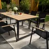 An outdoor dining set on a patio with greenery in the background. Náhled obrázku produktu