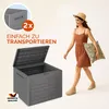 A woman walks past a storage box, carrying a cushion. The scene is set against a light background. Produktbild-Vorschau
