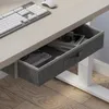 A close-up view of a desk drawer with items inside, showing a keyboard and mouse on the desk surface. Náhled obrázku produktu