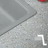 A close-up view of a gray granite sink and a speckled gray countertop. Produktbild-Vorschau