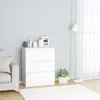 A white chest of drawers with decorative items on top, placed next to a sofa and in front of a window with sheer curtains. A rug is on the floor. Voir les images du produit