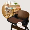 A baby sitting in a high chair at a table, with a close-up of the high chair in the foreground. Voir les images du produit
