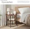 A bedside table with a lamp, books, and decorative items next to a bed. Produktbild-Vorschau