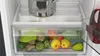 A close-up view of the interior of a refrigerator, showing a crisper drawer filled with various fruits and vegetables, and a pot on the shelf above. Produktbild-Vorschau