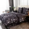 A bedroom scene with a bed dressed in black bedding with a white leaf pattern. Náhled obrázku produktu