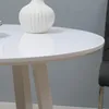 A close-up of a white, high-gloss round table with a white vase on it. Produktbild-Vorschau