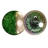 An open tin containing green glitter and a white ball, with the lid showing a cartoon monster and text. Podgląd zdjęcia produktu