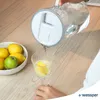 A person is pouring water from a glass pitcher into a glass with lemon slices. A bowl of lemons is on the side. Náhľad obrázku produktu