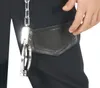 A close-up of a person's hand reaching into a black pocket on black pants, with a chain and handcuffs attached to the pocket. Anteprima dell’immagine prodotto