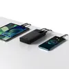 A black power bank is shown charging two smartphones and a tablet on a white surface. Podgląd zdjęcia produktu