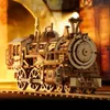 A wooden model of a steam locomotive on a track, with a warm, blurred background. Náhľad obrázku produktu