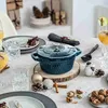 A table setting with a teal Dutch oven, drinks, and holiday decorations. Náhled obrázku produktu