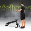 A man is using a multi-functional workout bench with a cable system. The word "Volume" is displayed in large, glowing letters in the background. Náhľad obrázku produktu