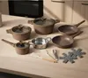 A set of cookware and utensils arranged on a wooden countertop. Voir les images du produit