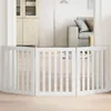 A white wooden pet gate is set up in a doorway, separating two rooms. The room behind the gate has a couch and a floor lamp. Voir les images du produit