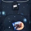 A close-up view of a dark blue backpack with a space-themed pattern, featuring a buckle and a patch of a spaceship. Produktbild-Vorschau