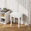 A white vanity stool is placed on a wooden floor next to a white shoe rack with shoes inside. The background features a wall with vertical white and gray stripes. Anteprima dell’immagine prodotto
