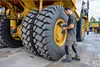 A mechanic is working on the large tires of a yellow construction vehicle. Voir les images du produit