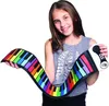 A young girl is holding a rainbow-colored roll-up piano. Produktbild-Vorschau