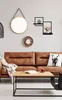 A living room scene with a brown leather sofa, coffee table, and wall decor. Produktbild-Vorschau