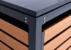 A close-up view of the corner of a trash can enclosure, showing the metal frame and the WPC (wood-plastic composite) siding. Produktbild-Vorschau