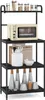 A black metal kitchen shelf unit with a microwave and various kitchen accessories displayed on its shelves. Náhled obrázku produktu