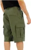 A person wearing green cargo shorts, viewed from the side. Náhled obrázku produktu