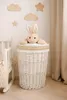 A nursery or child's room with a white wicker laundry basket, a plush bunny toy on top, and wooden cloud and star decorations on the wall. Produktbild-Vorschau