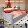 A grey upholstered bed frame with integrated LED lighting and shelves, shown in a bedroom setting with a rug and artwork. A smartphone app interface and remote control are also visible, indicating smart features. Voir les images du produit
