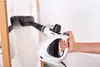 A hand is holding a white and black steam cleaner and cleaning a glass surface. Podgląd zdjęcia produktu