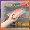 A hand holding vacuum-sealed carrots inside a refrigerator. Podgląd zdjęcia produktu