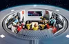 A toy spaceship bridge with several figures seated at consoles, with a starry background visible through a window. Podgląd zdjęcia produktu