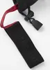 Close-up of a black glove with a red strap and a black fabric tag with embossed text. Náhľad obrázku produktu