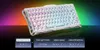 A white mechanical keyboard with RGB lighting is displayed on a reflective black surface with a colorful gradient background. Below the keyboard, there are four control buttons with text and icons. Produktbild-Vorschau