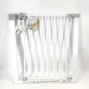 A white metal safety gate is laid flat against a white background. It is partially open and has some accessories and instructions attached. Produktbild-Vorschau