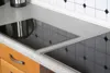A close-up view of a modern kitchen countertop with a built-in induction hob. Anteprima dell’immagine prodotto