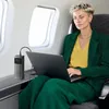 A woman is using a laptop and a power bank on an airplane. Produktbild-Vorschau