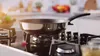 A frying pan sits on a gas stove in a kitchen. Produktbild-Vorschau