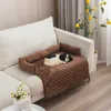 A dog bed cover is placed on a sofa with a toy dog on it. A plant with lemons is in the background. Náhled obrázku produktu