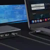 A Ugreen USB-C docking station is connected to a laptop, which is displaying a streaming service interface. Another display is visible in the background, suggesting a multi-monitor setup. Produktbild-Vorschau