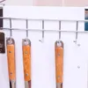 Kitchen utensils hanging on a rack mounted on a door. Produktbild-Vorschau