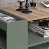 A close-up view of a coffee table with a newspaper in a green compartment and a camera on a stack of books. Náhled obrázku produktu