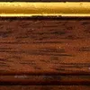 A close-up view of a wooden picture frame with a gold accent. Produktbild-Vorschau